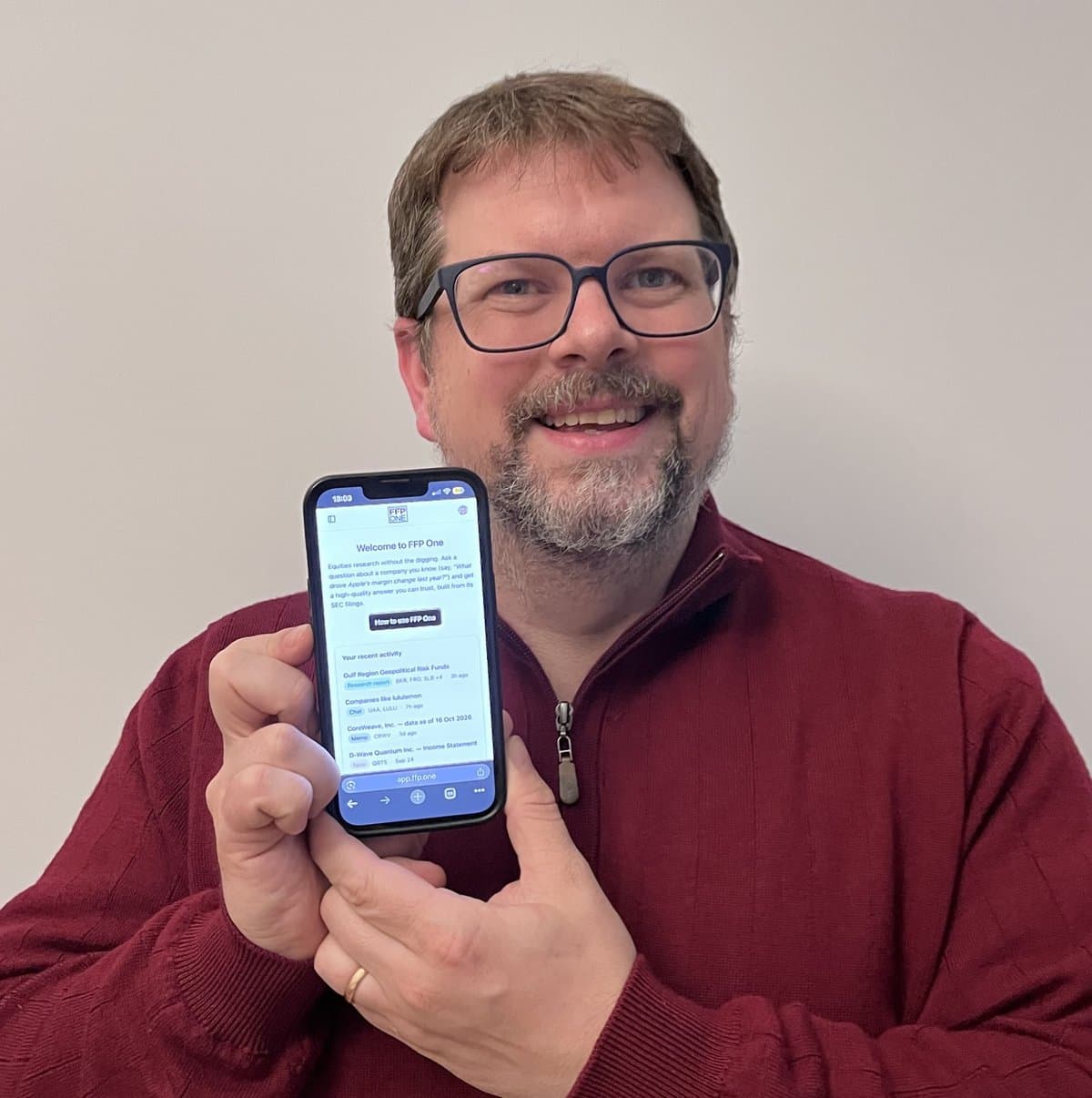 Randall Helms, founder of FFP One, holding a phone that shows the FFP One home screen.